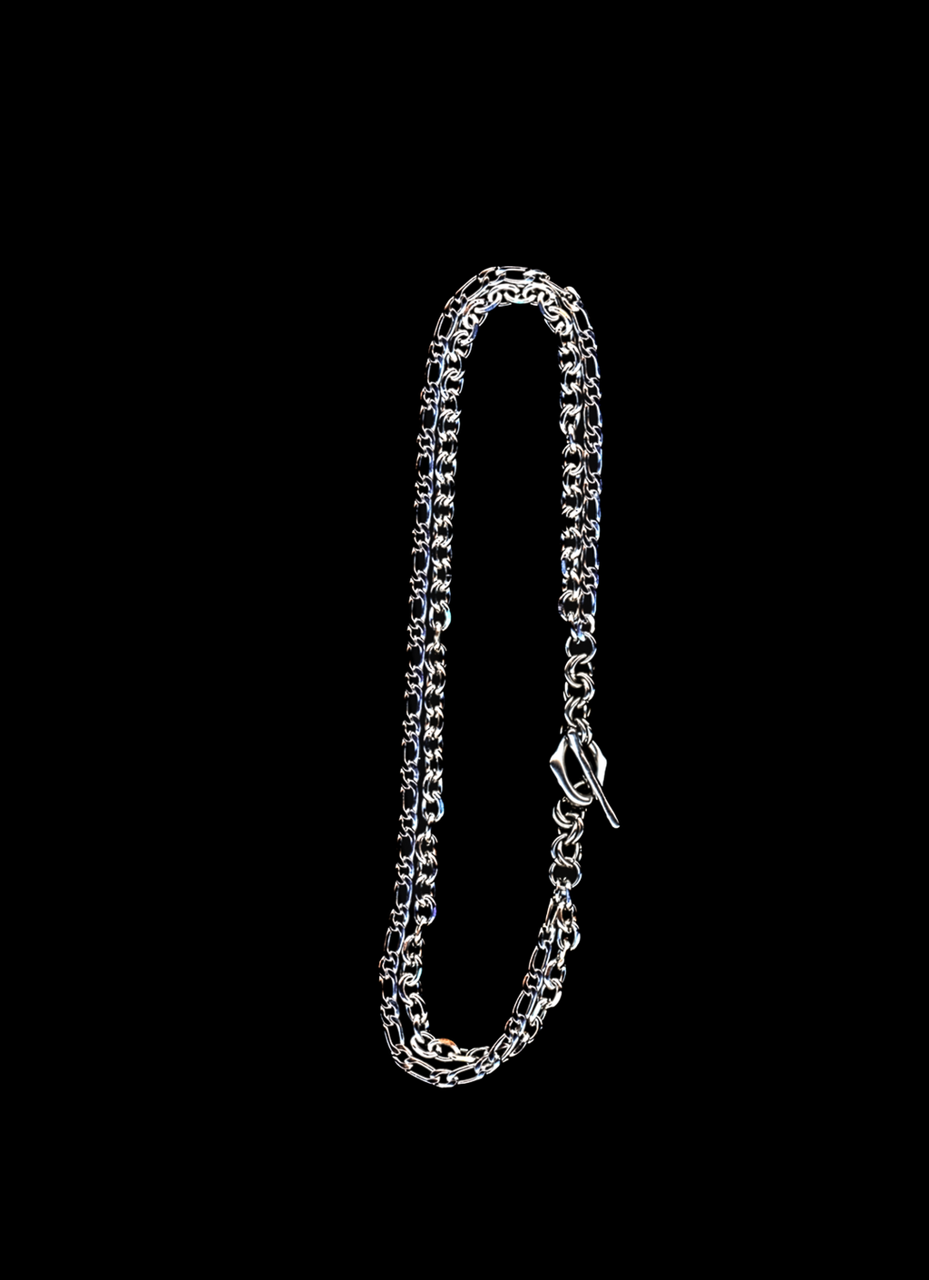 Stainless steel chain necklace with double chain strand and organic toggle closure on a black background