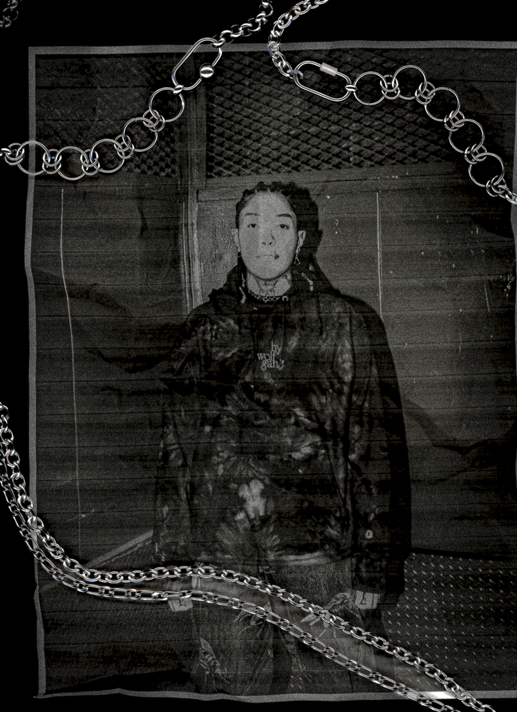 Scanned photo of person wearing a dark jacket with chains in front of a textured wall with bywolfgang chains overlayed on scanner.